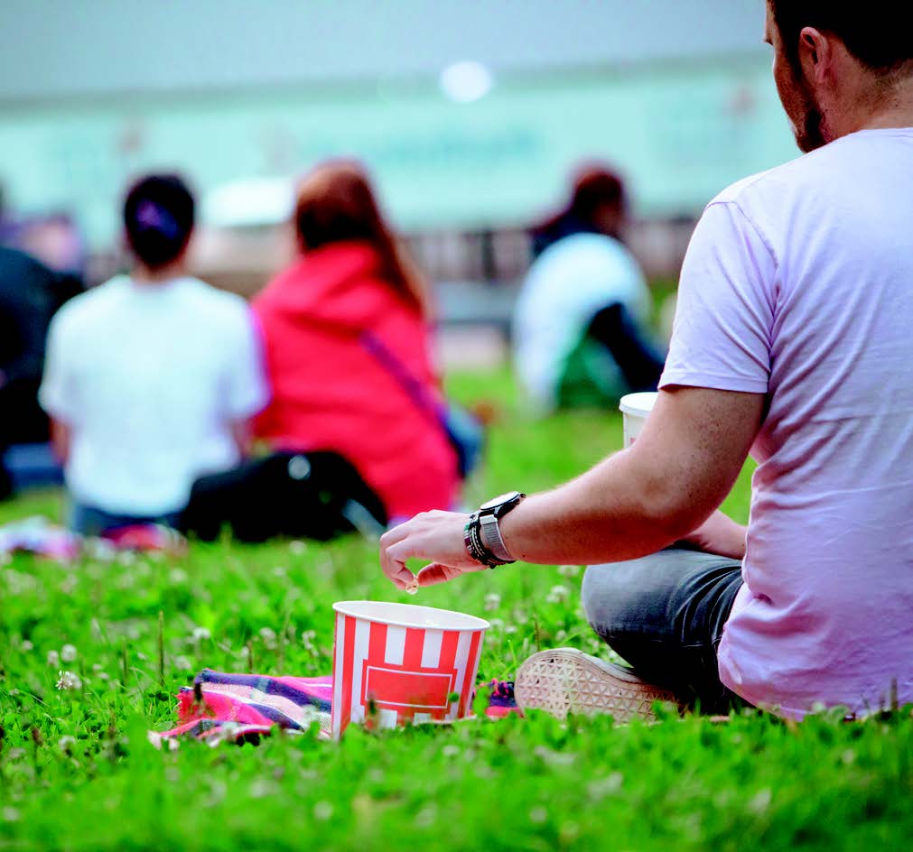 Man eating popcorn in the park while watching a movie