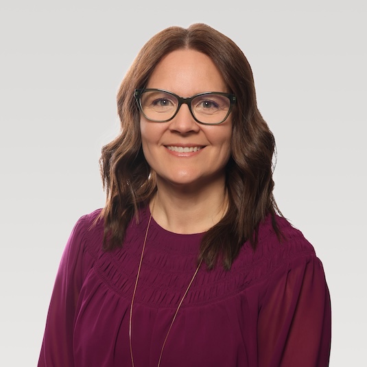 Woman in brown hair and glasses smiling