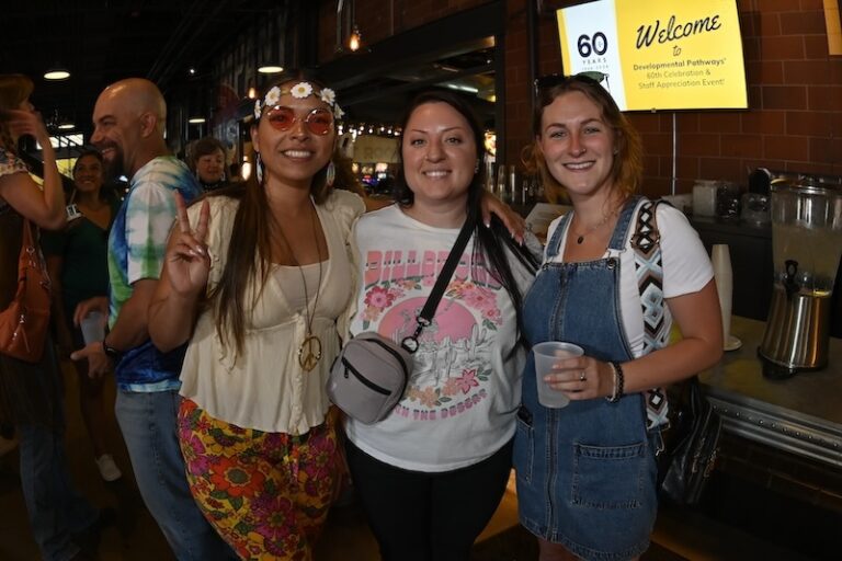 3 women with arms around eachother dressed in 60th attire