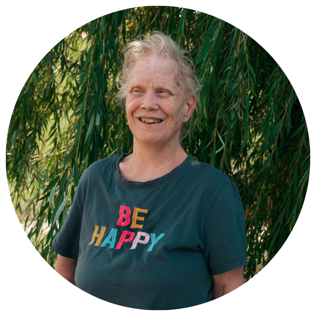 Smiling woman with shirt that says "Be Happy" – the faces of people we serve.